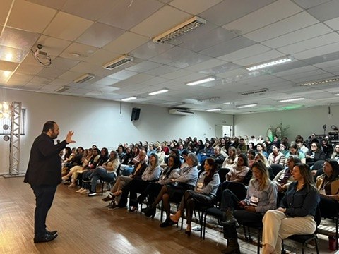 Renan Sargiani gesticulando em sala de formação diante de uma plateia de educadores